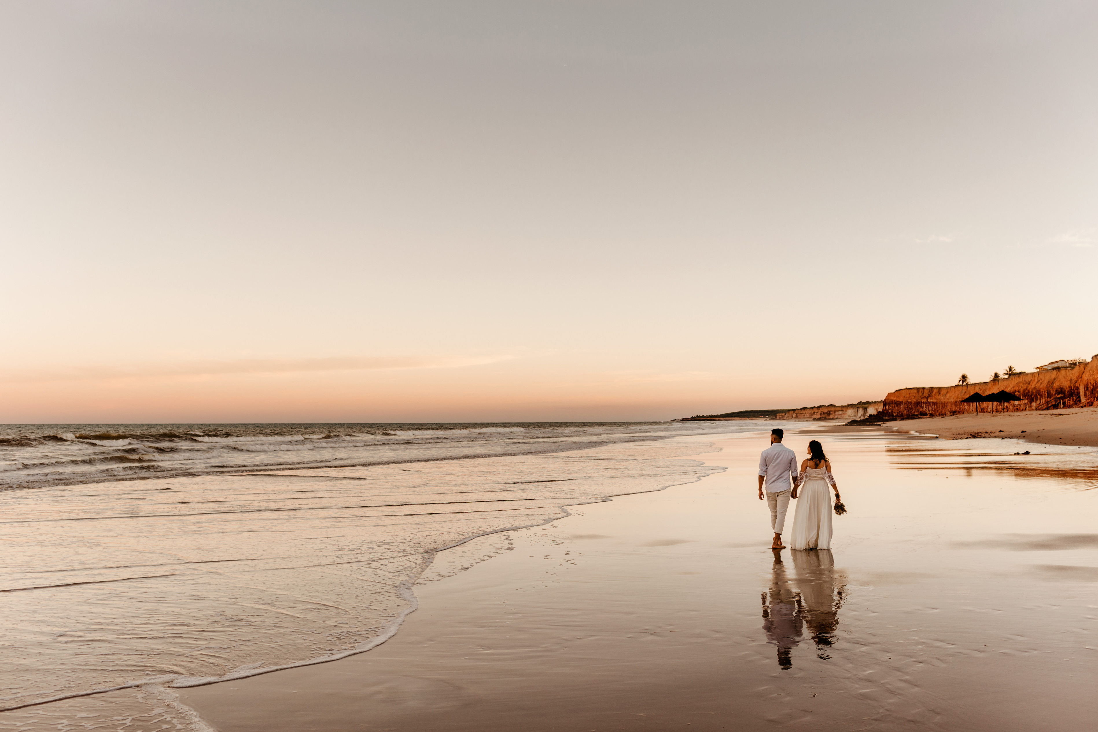 Couple in wedding wear walking along seashore